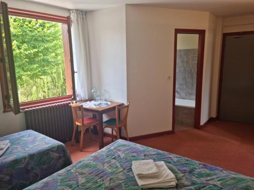 a room with two beds and a table and a window at Au Pont de la Ginéze in Barjac