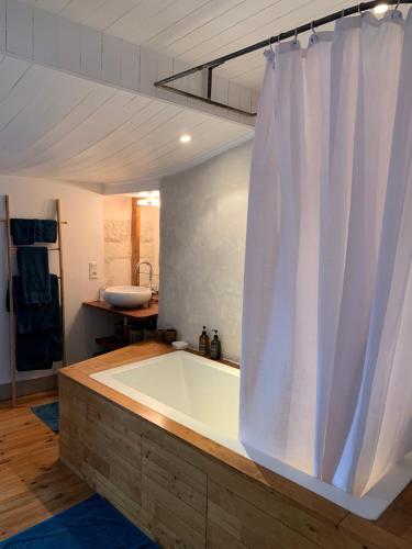 La salle de bains est pourvue d'une baignoire et d'un rideau de douche blanc. dans l'établissement Maison Face au Soleil, au Bois-Plage-en-Ré