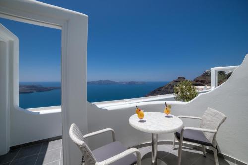 a balcony with a table and chairs and a view of the ocean at Remvi Suites in Firostefani