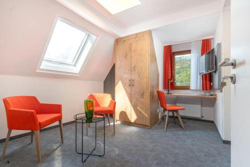 a room with orange chairs and a desk and a window at Parkhotel Cochem in Cochem