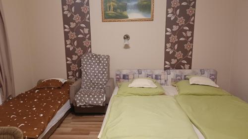 1 dormitorio con 2 camas individuales y 1 silla en Kaszivendégház, en Hajdúszoboszló