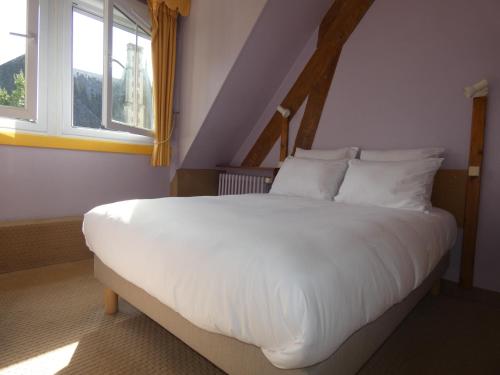 a bedroom with a large white bed with two windows at Hôtel de France in Pont-lʼÉvêque