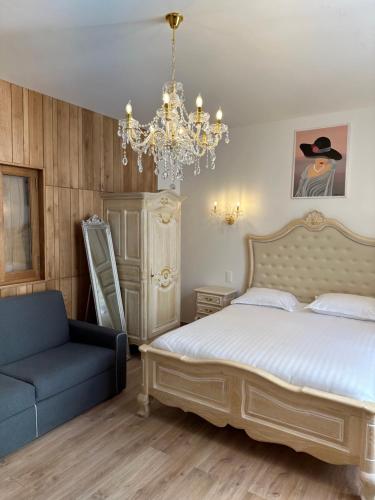 a bedroom with a bed and a chair and a chandelier at Studio familial Maison de L'église du Couvent in Narbonne