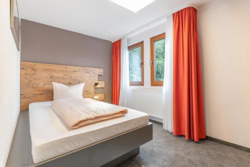 a bedroom with a bed with an orange curtain at Parkhotel Cochem in Cochem