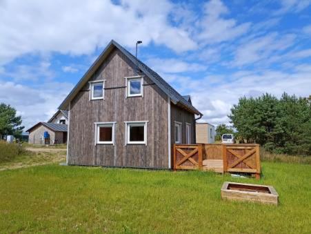 a house in a field with a green yard at Drewniany domek na kaszubach u Oli in Niesiołowice
