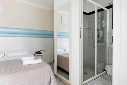 y baño con cama y ducha acristalada. en Hotel Villa Argia Rimini Marina Centro en Rímini