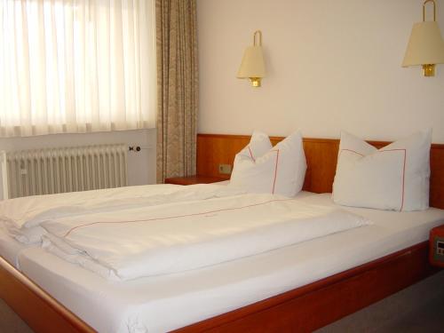 a large bed with white sheets and pillows at Hotel Brunnenhof in Bad Füssing