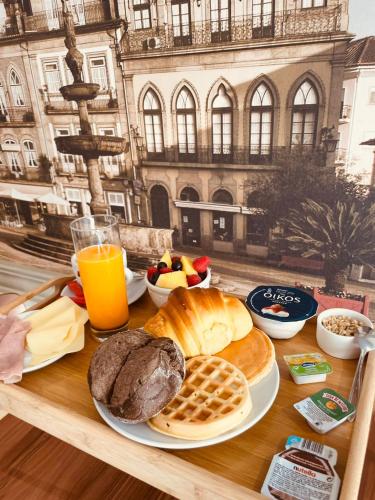 a table topped with bread and waffles and orange juice at Camões Apartments in Ponte de Lima