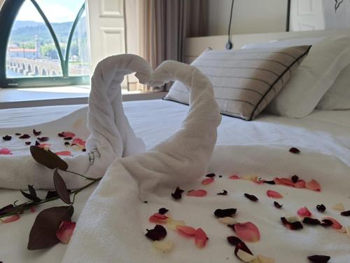 a towel shark laying on a bed with flowers on it at Camões Apartments in Ponte de Lima