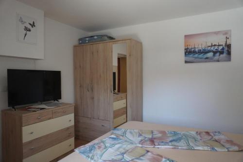 um quarto com uma cama e uma cómoda com uma televisão em Apartmani Skledar em Vodice