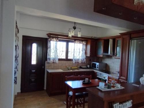 a kitchen with wooden cabinets and a table in it at κτήμα ΝΟΣΤΟΣ in Aígio