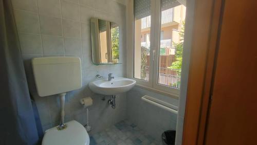 ein Bad mit einem Waschbecken, einem WC und einem Fenster in der Unterkunft Hotel Eriale in Rimini