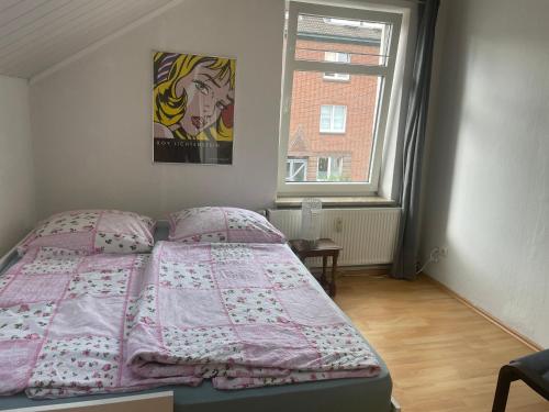 a bedroom with a bed with a pink comforter and a window at Fewo Itzehoe in Itzehoe