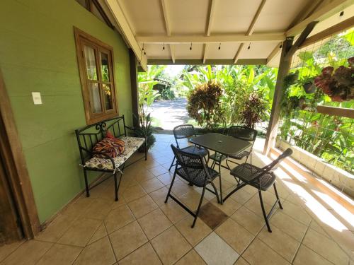 een patio met een tafel en stoelen op een veranda bij Cabina Rancho la Merced in Uvita