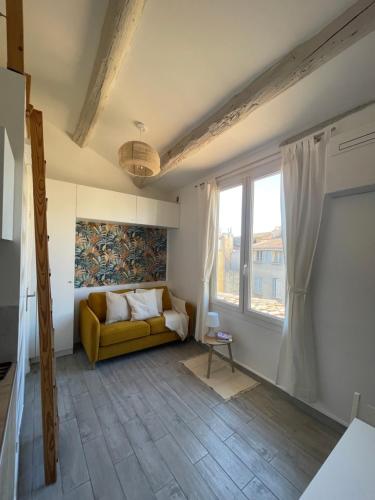 - un salon avec un canapé jaune et une fenêtre dans l'établissement Beau studio au cœur d’Aix et du Cours Mirabeau, à Aix-en-Provence