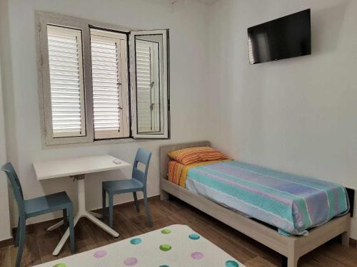 1 dormitorio con cama, escritorio, mesa y sillas en La casa di Enzo, en Tre Fontane