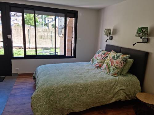 a bedroom with a bed and a large window at Studio Gîtes Au Pont de la Ginéze in Barjac