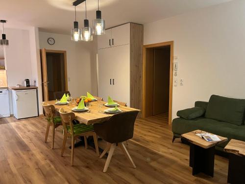 a living room with a table and a green couch at Appartement NaMoll in Ausserfragant