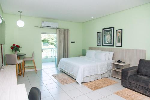 a bedroom with a bed and a chair and a couch at Hotel Equinocios Executive in Barcarena