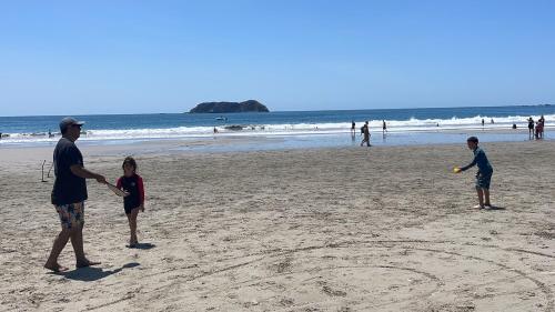 a man and two children playing with a frisbee on the beach at Casa Paraiso Tropical in Parrita