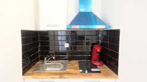 a small kitchen with a sink and a blue hood at Résidence de Rose, Bas, La Courneuve in La Courneuve