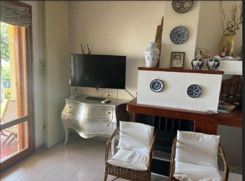 a living room with a television and a table with chairs at Villetta Indipendente Sardegna in Villaputzu