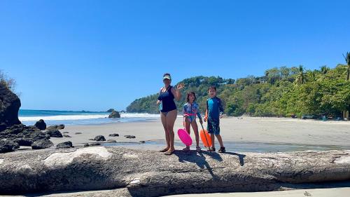 a family standing on a rock on the beach at Casa Paraiso Tropical in Parrita