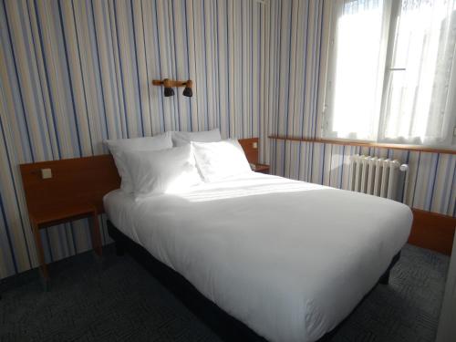 a large white bed in a room with a window at Hôtel de France in Pont-lʼÉvêque