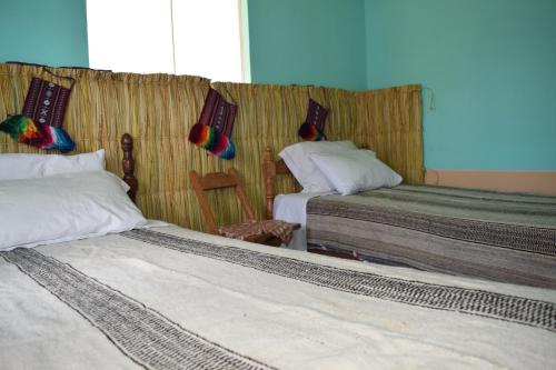 a bedroom with two beds and a wall with at Taquile Sumaq Wasi - Casa de Felipe e Ines in Huillanopampa
