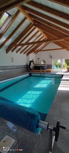 a large swimming pool in a building with a wooden ceiling at Chambres d’hôtes plateau des mille étangs in Belonchamp