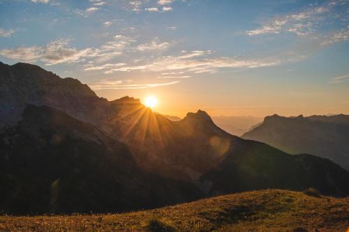 a sunset over a mountain range with the sun setting at La Capitale - Les Gîtes de L Argile in Barcelonnette