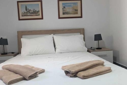 um quarto com uma cama branca e toalhas em Skordalos mezoneta em Áno Viánnos