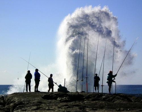 a group of people standing on a rock with fishing rods at Ocean View Villas F16 Port Edward in Port Edward