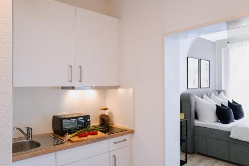 維斯馬的住宿－Designoase für 3 mit Blick auf den Wismarer Hafen，厨房配有白色橱柜、水槽和床。