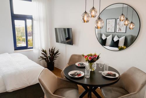 a living room with a table and chairs and a mirror at Designoase für 3 mit Blick auf den Wismarer Hafen in Wismar