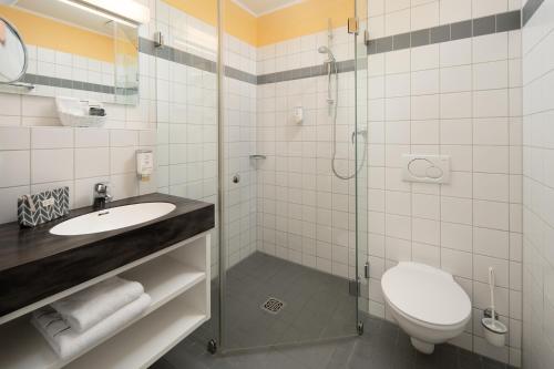 a bathroom with a shower and a toilet and a sink at Johanniter Gästehaus in Münster