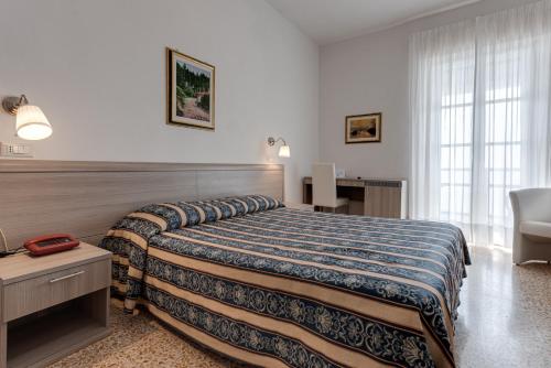 une chambre d'hôtel avec un lit et une chaise dans l'établissement Grand Hotel Vallombrosa, à Vallombrosa