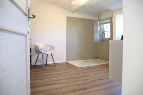 a room with a glass shower and a white chair at Ferienhaus Rabenbrunn in Arnstorf