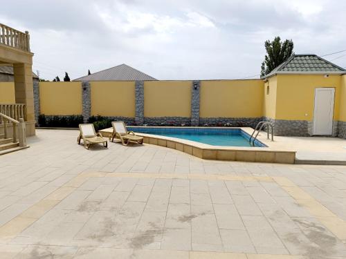 einen Pool in einem Garten mit zwei Stühlen und einem Haus in der Unterkunft Gilavar 3 bedrooms in Cǝnubi
