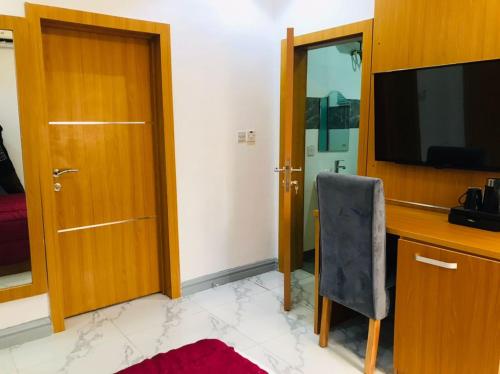 a room with a desk and a television and a chair at Dominance Events and Suites in Ibadan