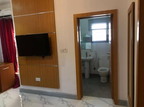 a bathroom with a toilet and a flat screen tv at Dominance Events and Suites in Ibadan