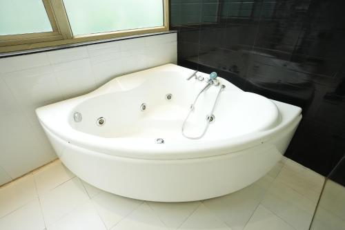 a white bath tub in a bathroom with a window at Downtown Cyber City in Gurgaon