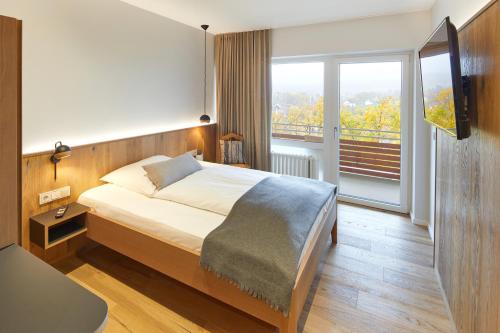 een slaapkamer met een bed en een groot raam bij Hotel Sonneck in Knüllwald