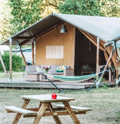 a tent with a picnic table and a hammock at Glamping Holten luxe safaritent 2 in Holten