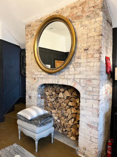 a mirror hanging on a brick fireplace with a bench at Château 9 Neuf in Newark upon Trent