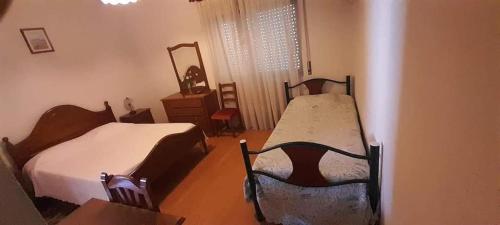 a bedroom with two beds and a table and a mirror at My Portugal in Vidago