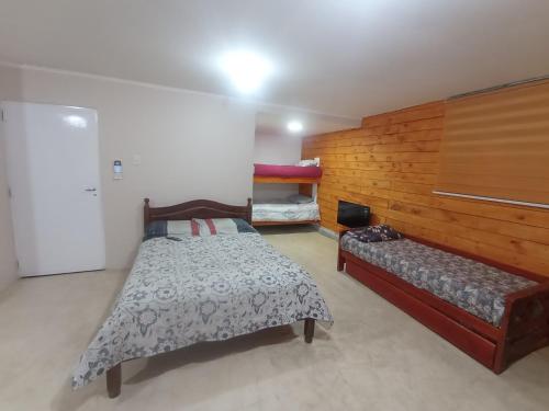 Un dormitorio con 2 camas y un banco. en Ayre Sureño en Río Gallegos