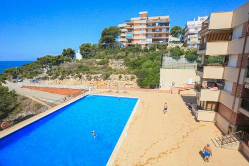 a swimming pool next to a beach and some buildings at CABO Palos 4 2 2 ONLY FAMILIES in Salou
