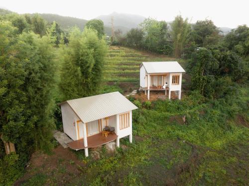 duas pequenas casas brancas num campo com árvores em Monko Villa em Pai