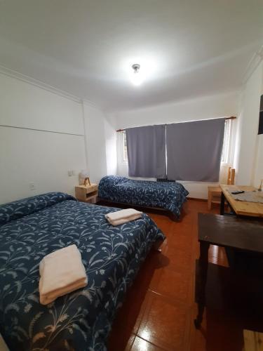 Habitación de hotel con 2 camas y escritorio en Bariloche Natural en San Carlos de Bariloche